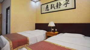 A hotel room with two beds, each with a red and white bedspread, a wooden nightstand with a lamp, and a framed Chinese calligraphy on the wall. - Gaochun Tianhao Hotel (Gaoyi)