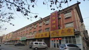 A multi-story building with several commercial establishments on the ground floor, including a pharmacy and a hair salon. - Gaochun Tianhao Hotel (Gaoyi)