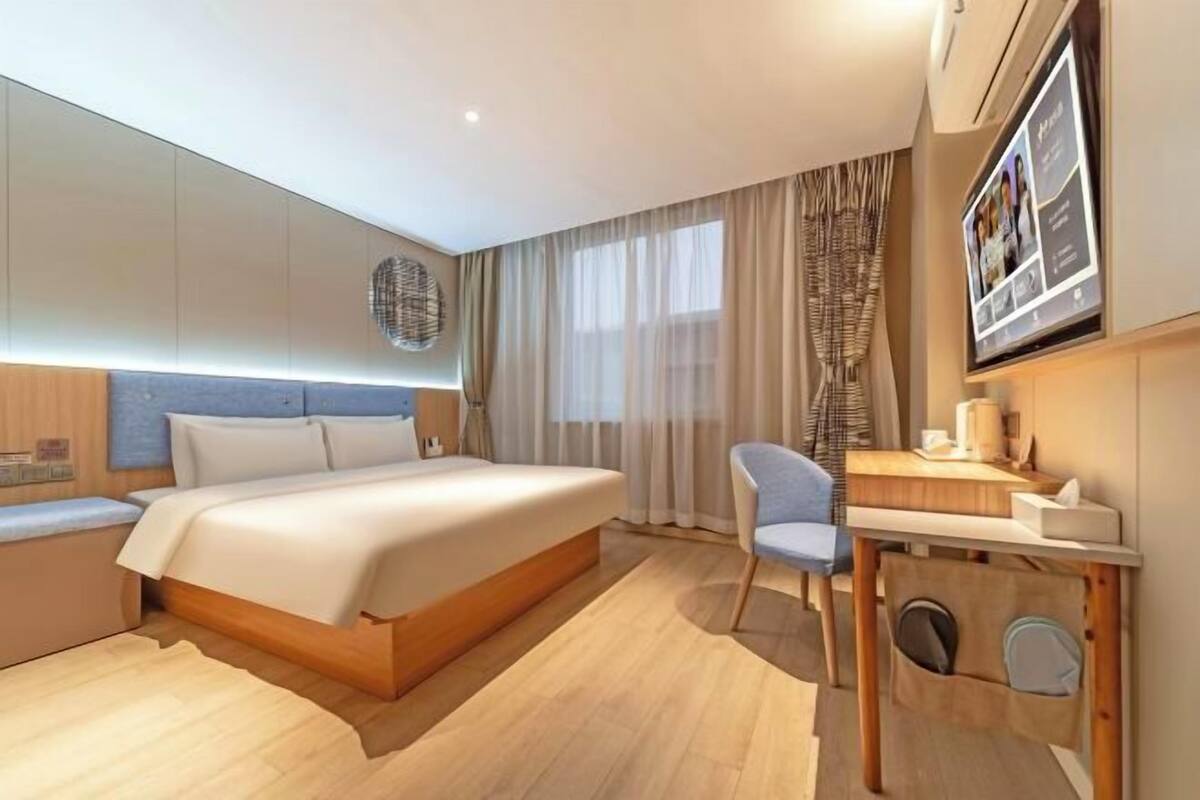 Quarto de hotel moderno com cama, escrivaninha e cadeira.