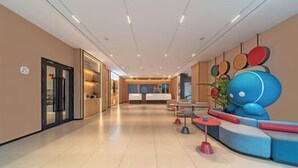A modern lobby with a reception desk, seating area, and a large abstract sculpture. - Home Inn (Linyi Luozhuang District Government) (Linyi)