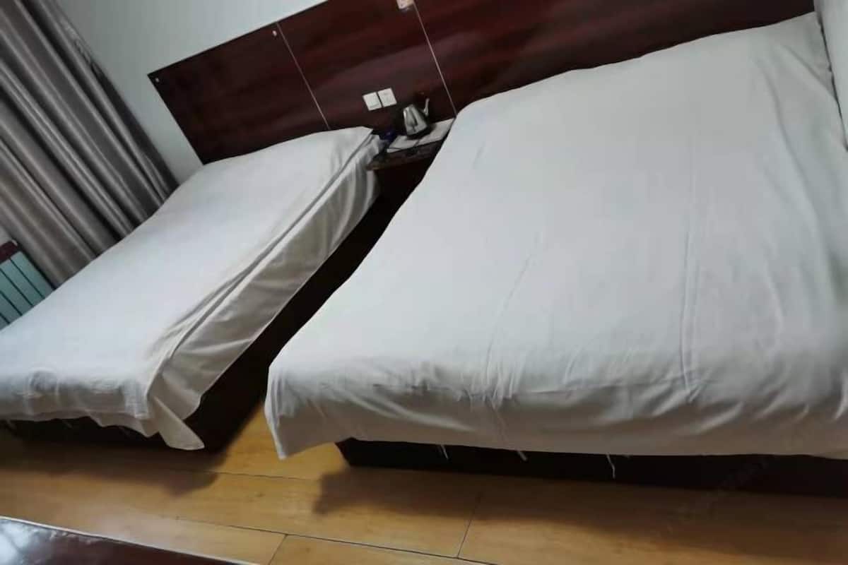 Habitación de hotel con dos camas, cabecero de madera y suelo de baldosas.