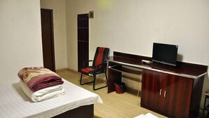 A hotel room with a bed, a desk with a computer, a chair, and a wardrobe.