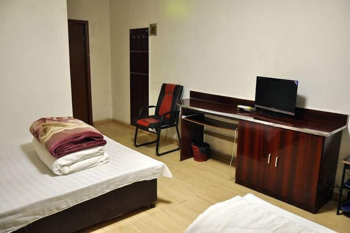 Una habitación de hotel con una cama, un escritorio con una computadora, una silla y un armario.