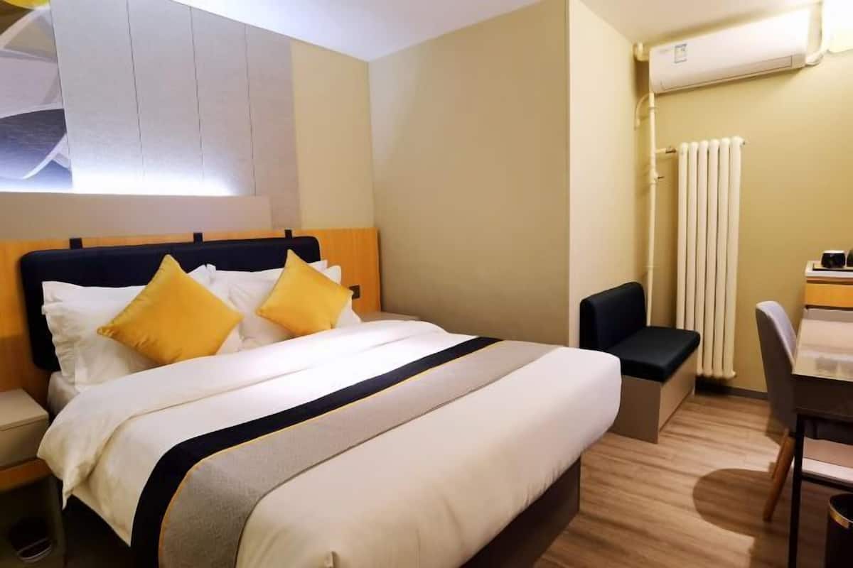 Una habitación de hotel con cama, escritorio, silla y radiador.