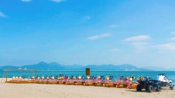 A beach with a row of boats and a dune buggy parked on the sand.