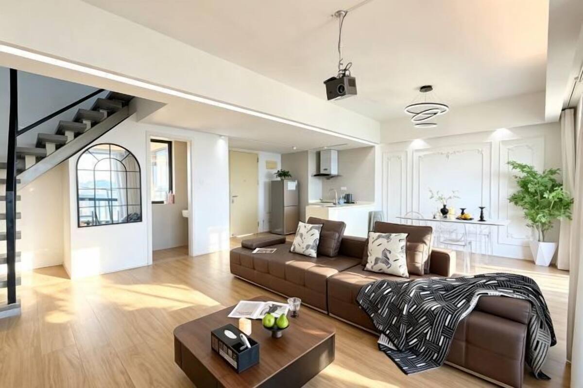 Una sala de estar moderna con sofá, mesa de centro y una escalera.
