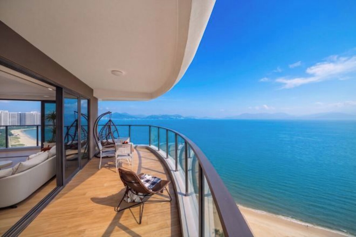Un balcón con vista al mar, una zona de estar y un muro de cristal.