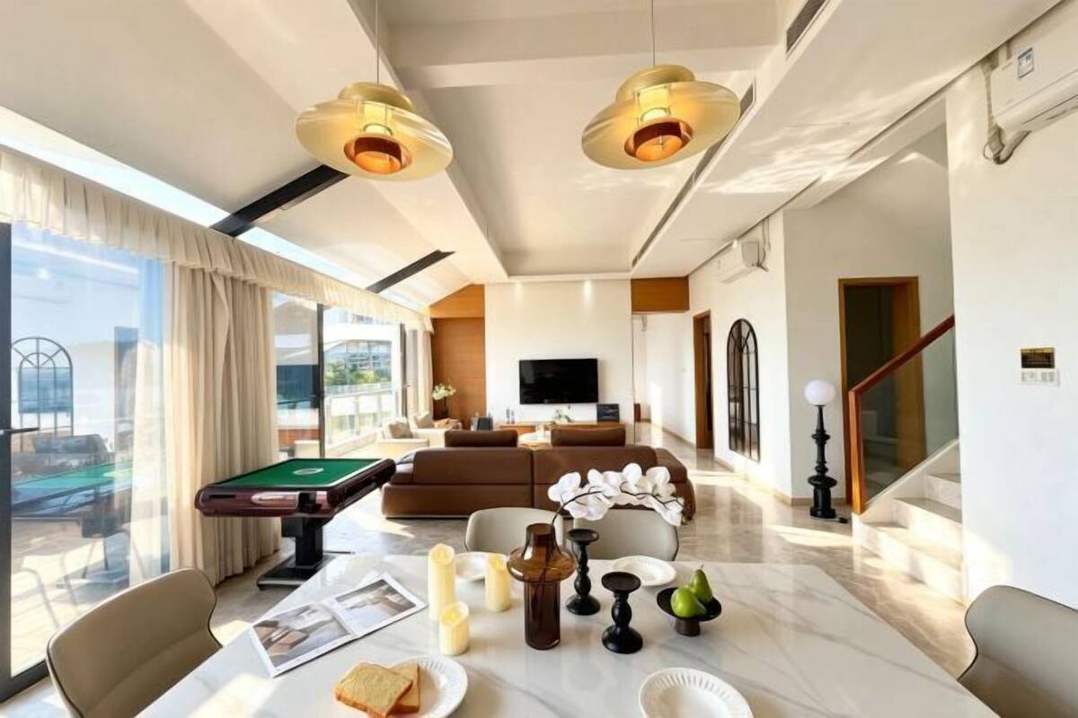 Una sala de estar moderna con mesa de billar, asientos cómodos, televisor de pantalla plana y una escalera que lleva a otro nivel.