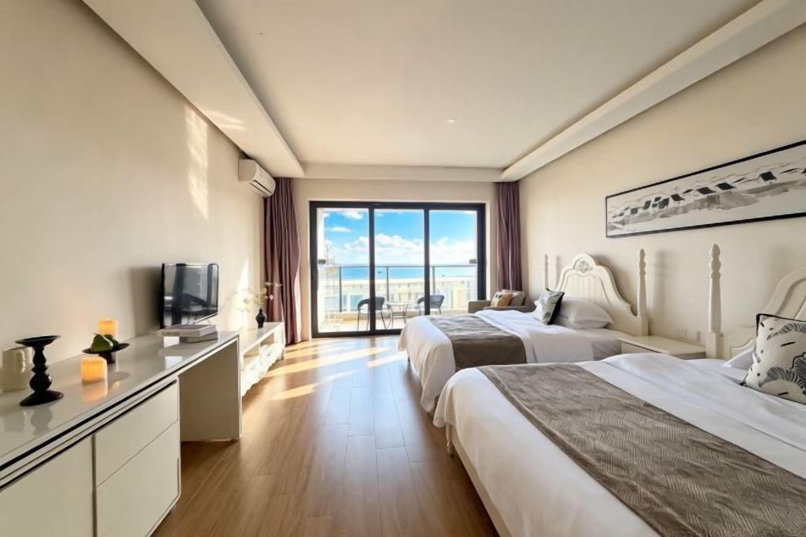 Habitación de hotel con dos camas, un escritorio, un televisor y un ventanal con vista a la ciudad.
