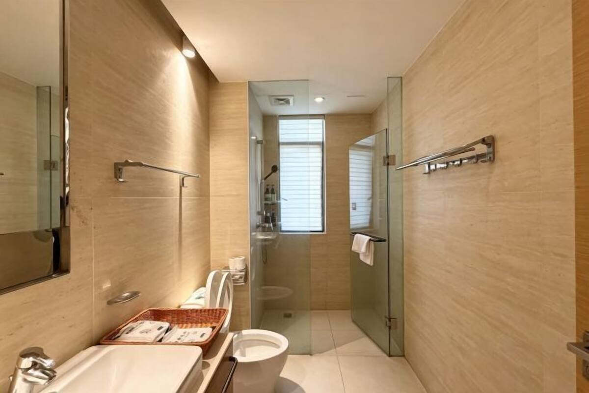 Un baño moderno con cabina de ducha de vidrio, tocador con espejo y inodoro.