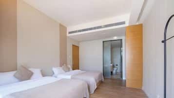 Ein modernes Hotelzimmer mit zwei Betten, Holzboden und Blick auf die Eingangshalle.