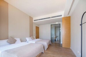 Una habitación de hotel moderna con dos camas, suelo de madera y vistas al pasillo.