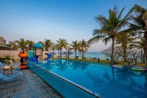 Una piscina amb tobogan, palmeres i vista a la platja.