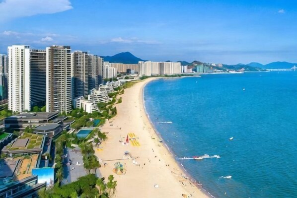 A coastal cityscape with high-rise buildings, a sandy beach, and a clear blue sea.