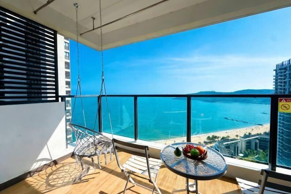 Un balcón con mesa y sillas, con vista a una playa y al océano.