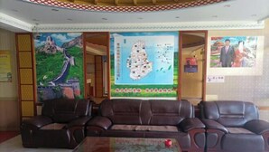 A lobby with leather sofas, a coffee table, and a map on the wall. - Prairie Pearl Express Hotel (Hexigten Banner)