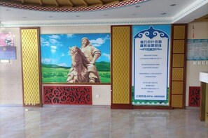 A lobby with a large mural, a reception desk, and a patterned wall design. - Prairie Pearl Express Hotel (Hexigten Banner)