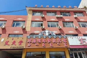 A multi-story building with a red facade and multiple air conditioning units. - Prairie Pearl Express Hotel (Hexigten Banner)