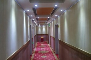 Een hotelgang met een rood tapijt, houten lambrisering en inbouwverlichting.