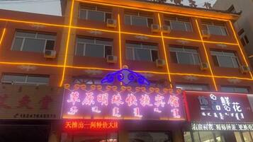 A building with multiple signs, including one with a blue car and another with Chinese characters.