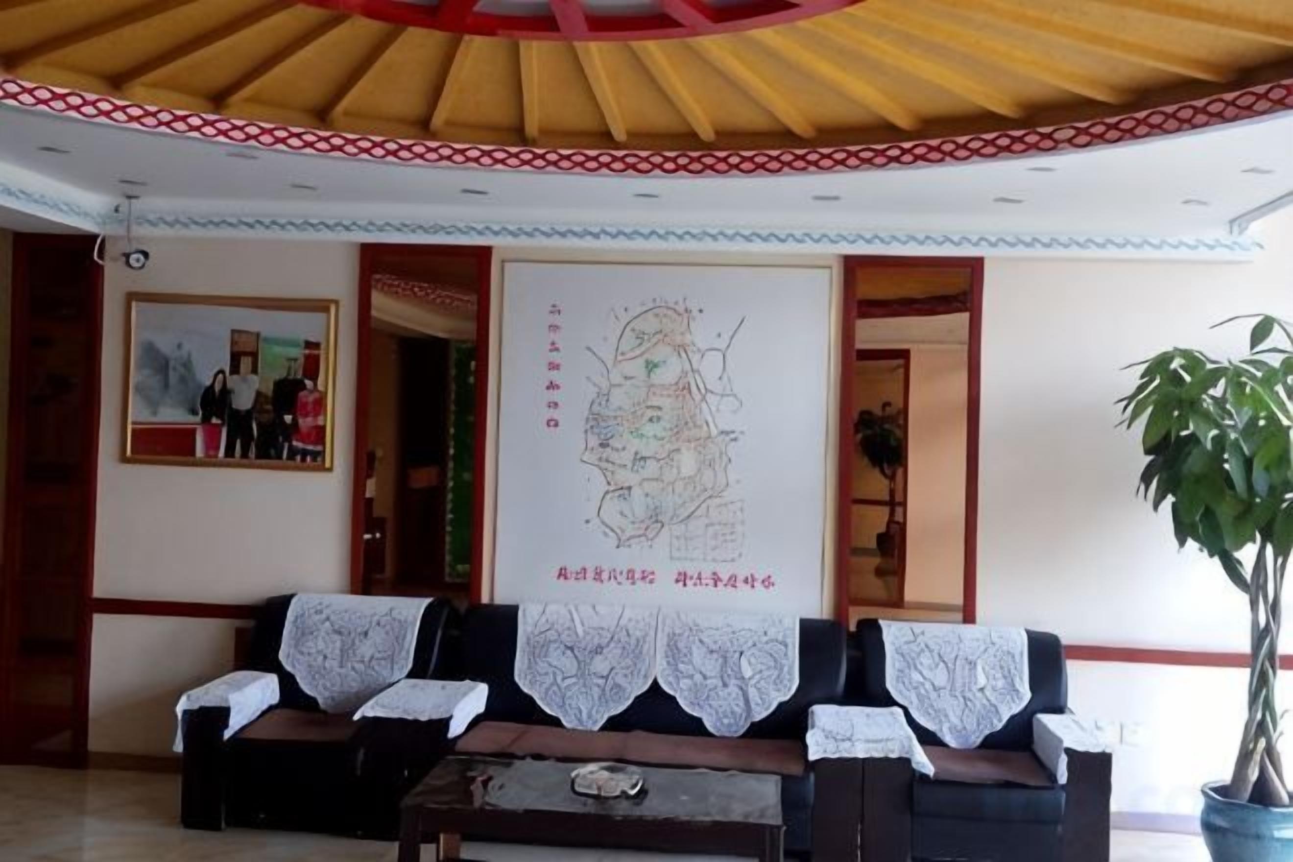 Una zona di accoglienza con una reception, un divano, una cartina grande e una pianta in vaso.