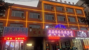 A multi-story building with illuminated signage, air conditioning units, and a visible entrance. - Prairie Pearl Express Hotel (Hexigten Banner)