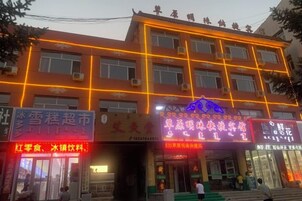 Un edificio de varios pisos con señalización iluminada, una entrada visible y unidades de aire acondicionado en el exterior.
