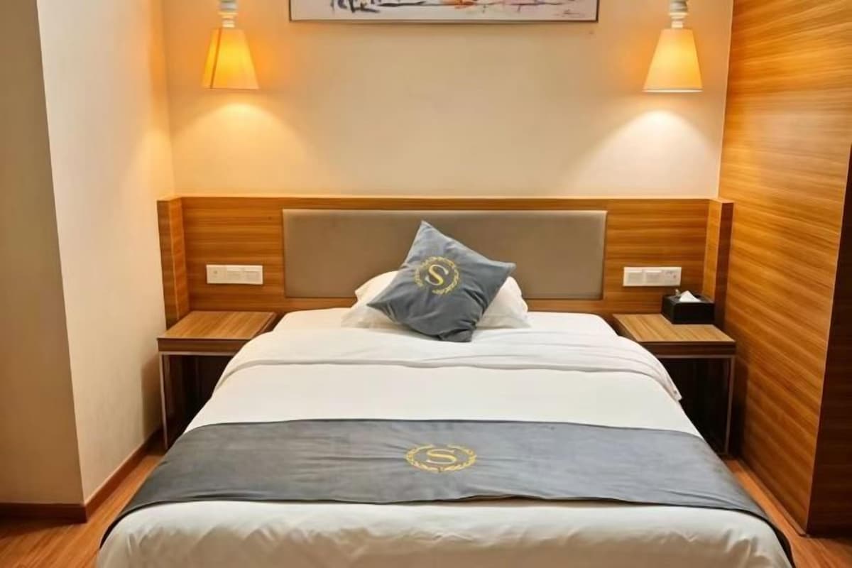 Een hotelkamer met een bed, nachtkastjes, een lamp en een wandlamp.