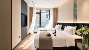 Una habitación de hotel con una cama, televisión, ventana con cortinas y un jarrón con flores.