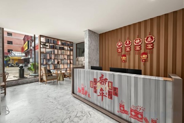 A hotel reception area with a wooden reception desk, a bookshelf, and a view of the street outside. - LAKE STAR Designer Curated Hotel (Quanzhou Ancient City Food Street) (Quanzhou)