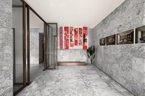 Een kamer met marmeren vloer, een glazen toegangsdeur en rode banners aan de muur.