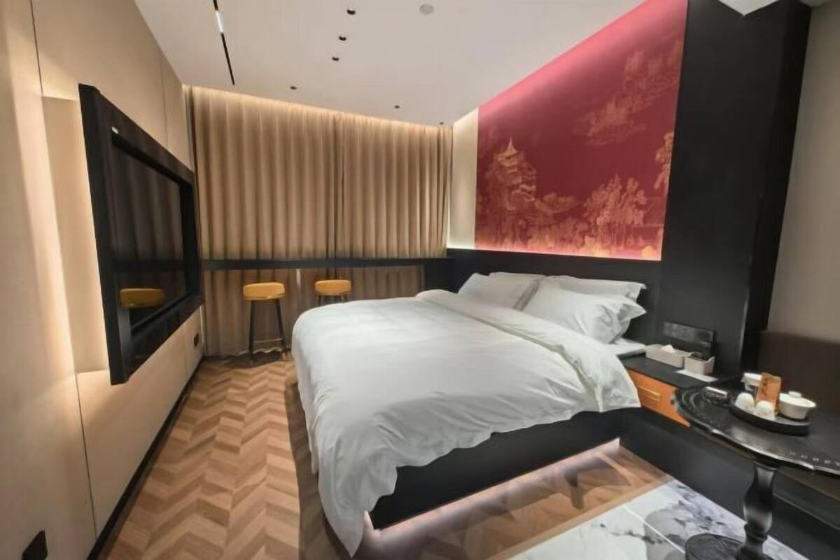 Una habitación de hotel moderna con una cama, mesita de noche y un mural grande en la pared.