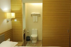 Un baño pequeño y funcional con tocador de madera, inodoro y perchero para toallas.