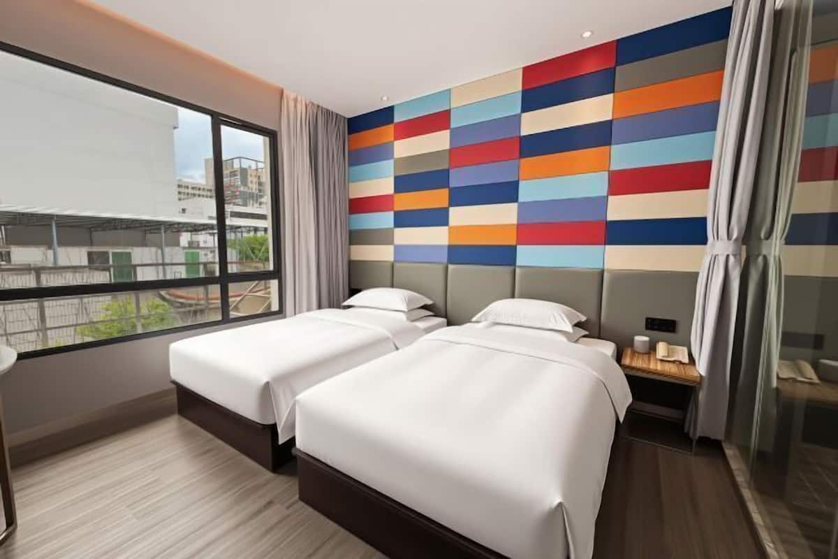 Habitación de hotel con dos camas, un ventanal grande y un diseño de pared colorido.