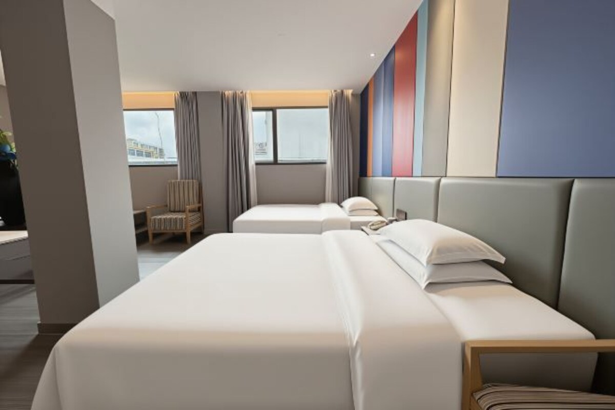 Een hotelkamer met twee bedden, een zithoek en uitzicht op de stad.