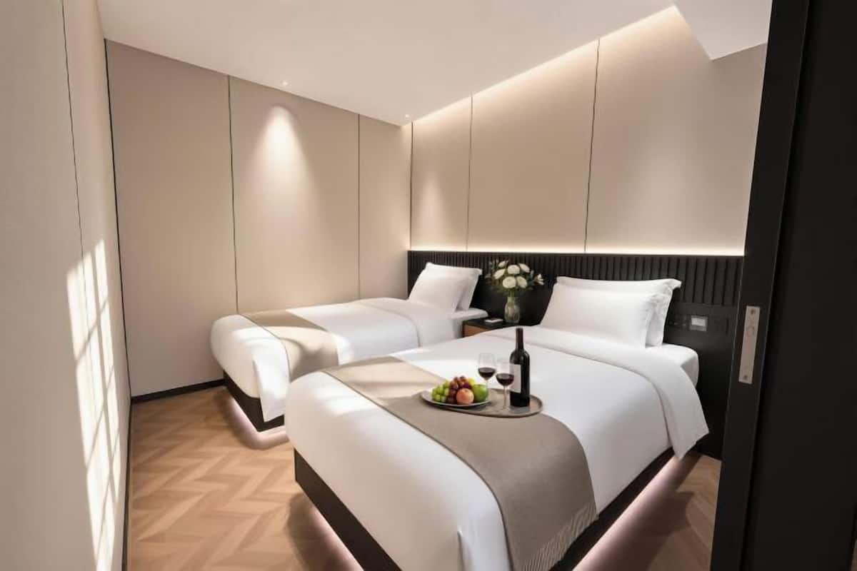 Una habitación de hotel moderna con una cama grande, mesitas de noche y un pequeño escritorio.