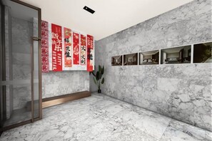 A room with a marble floor, a glass door, and a wall with red banners and a series of framed pictures. - LAKE STAR Designer Curated Hotel (Quanzhou Ancient City Food Street) (Quanzhou)