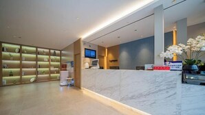 Un espace d’accueil d’hôtel avec un comptoir en marbre, un écran de télévision et un bureau de réception.