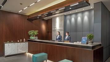 Una zona de recepción con un mostrador de madera, dos recepcionistas y un diseño moderno.