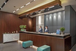 Een receptiegedeelte met een houten receptiebalie, twee receptionisten en een modern ontwerp.