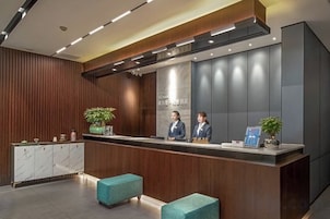 Una zona de recepción con un mostrador de madera, dos recepcionistas y un diseño moderno.