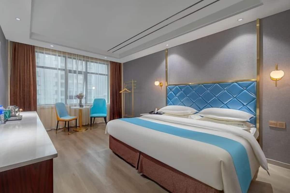 Una habitación de hotel con cama, escritorio, silla y ventana.