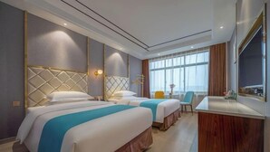 Een hotelkamer met twee bedden, een bureau, een stoel en een groot raam.