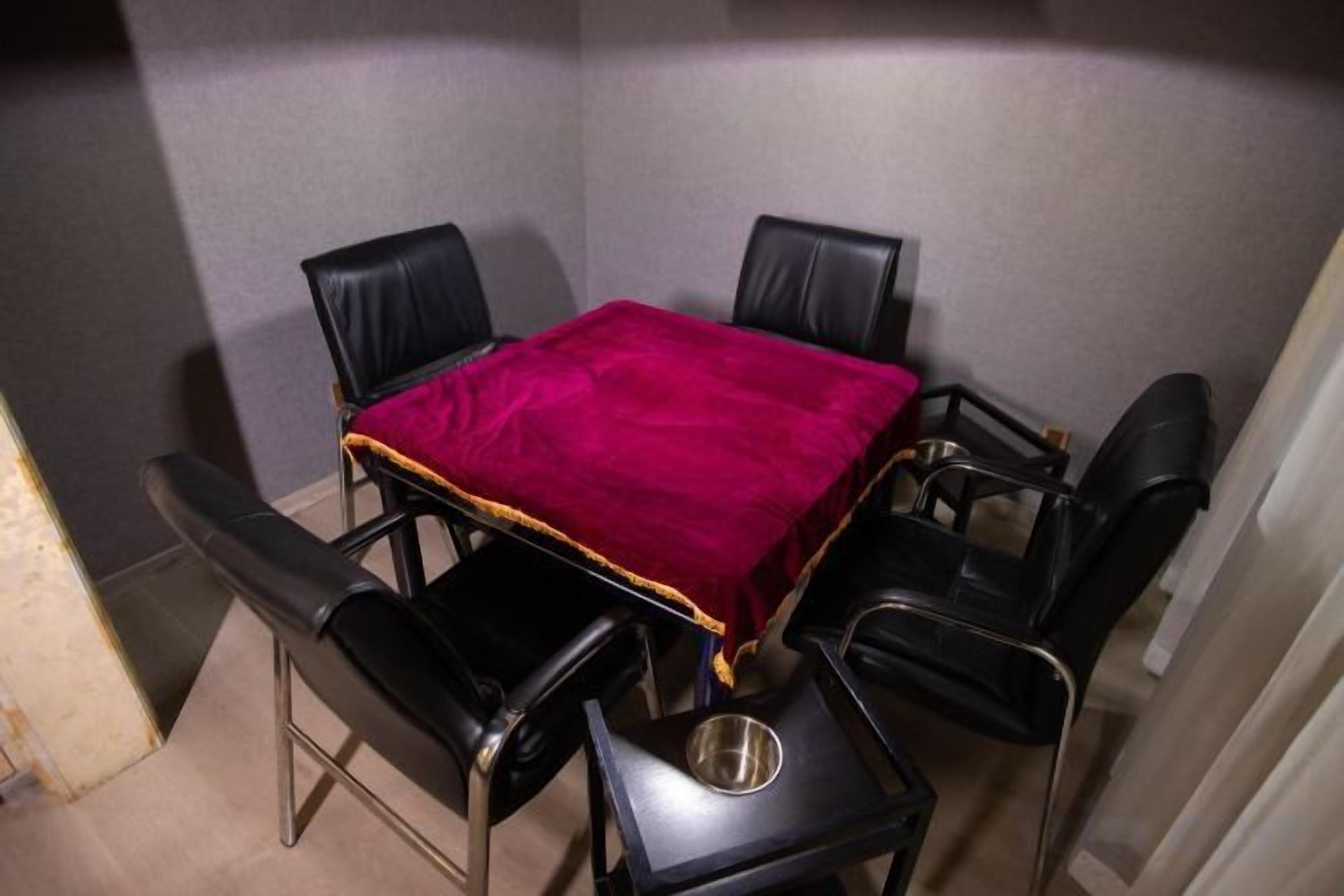 A small dining area with a table and four chairs, a metal bowl on the table, and a red tablecloth.