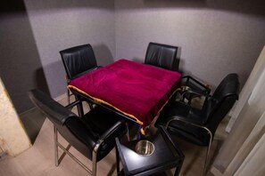 A small dining area with a table and four chairs, a metal bowl on the table, and a red tablecloth.