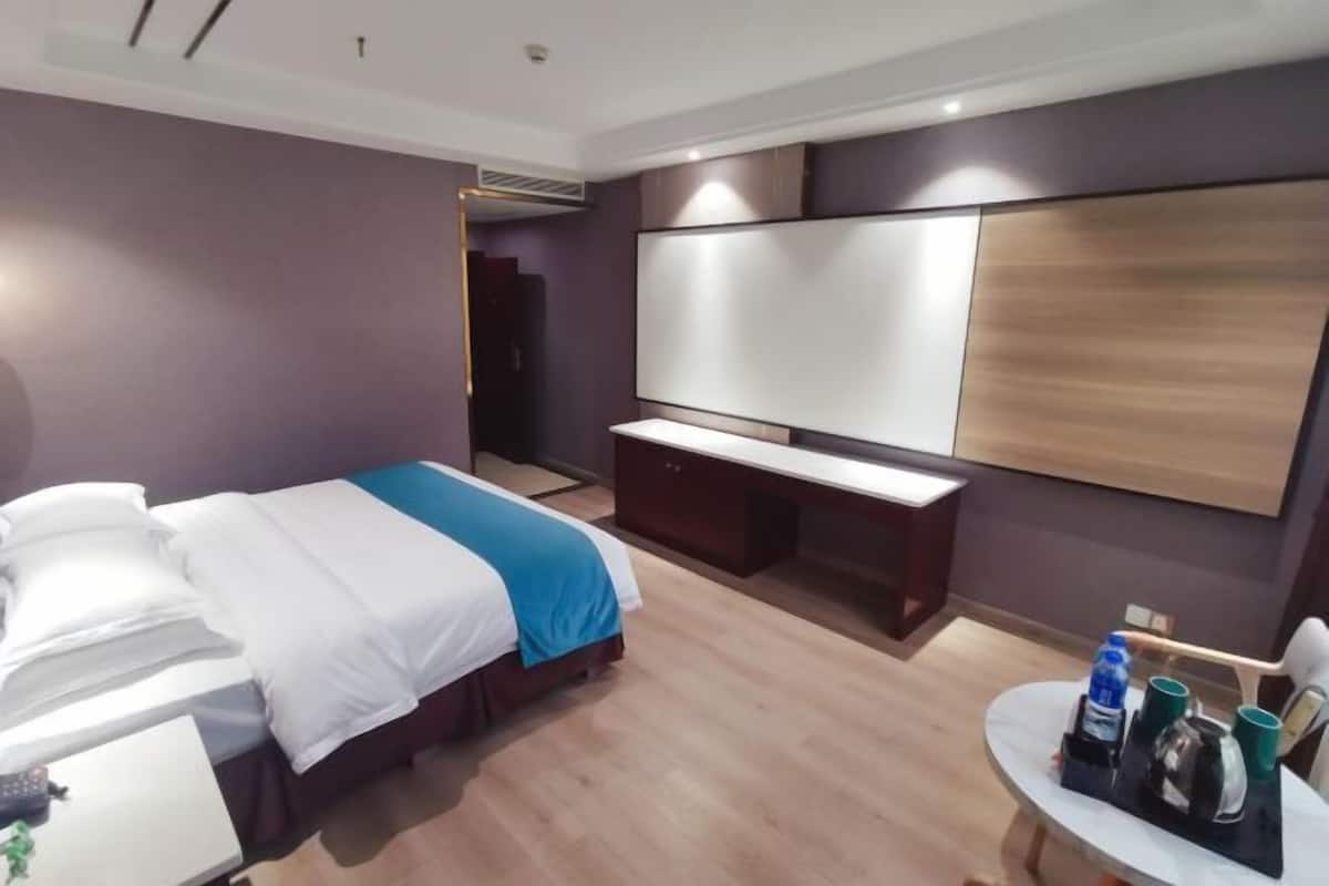 Una habitación de hotel con cama, mesita de noche y escritorio con silla.