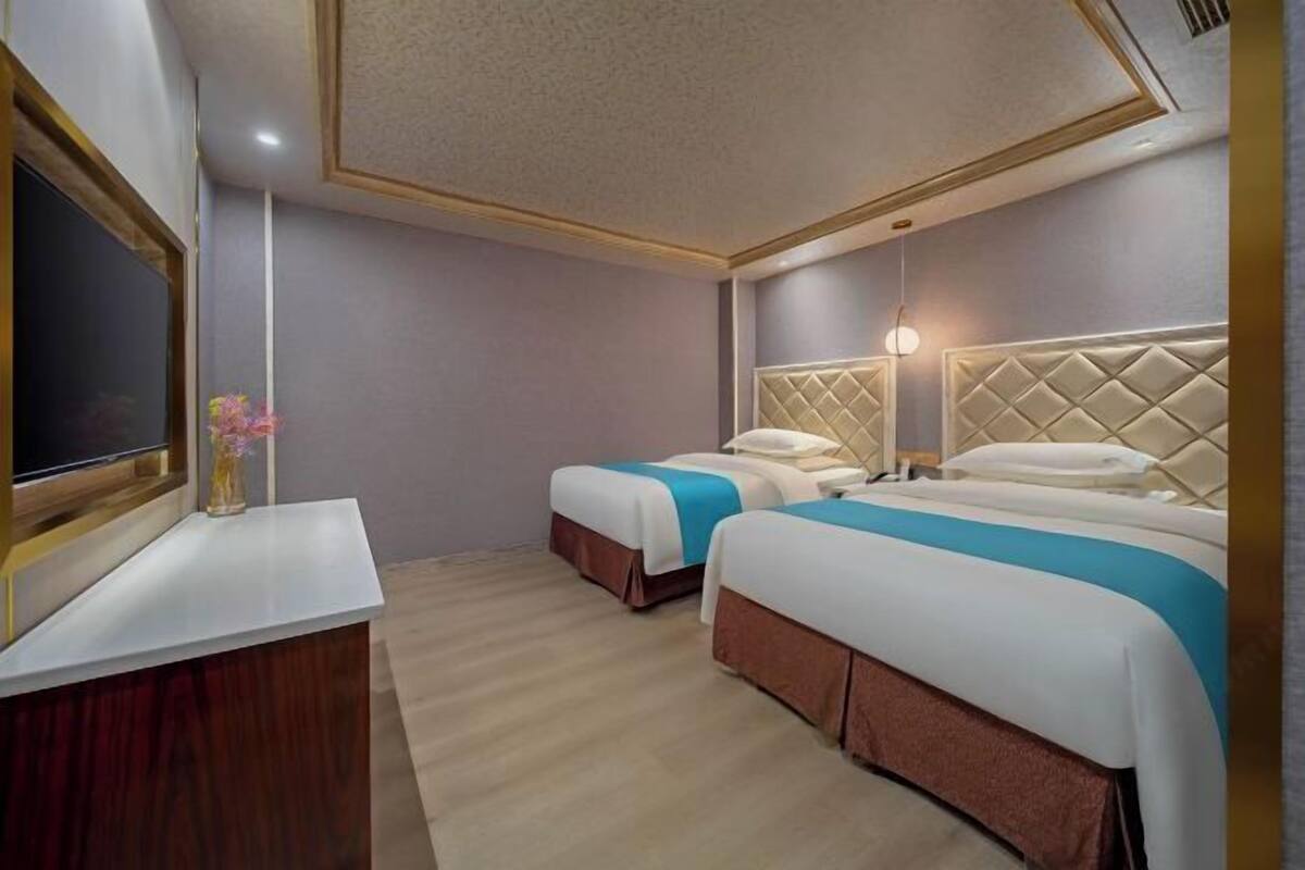Habitación de hotel con dos camas, un escritorio y un televisor.
