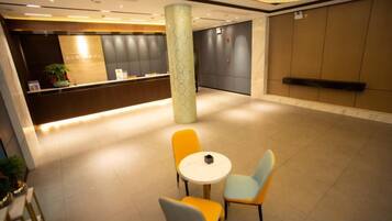 A hotel lobby with a reception desk, seating area, and a large pillar.