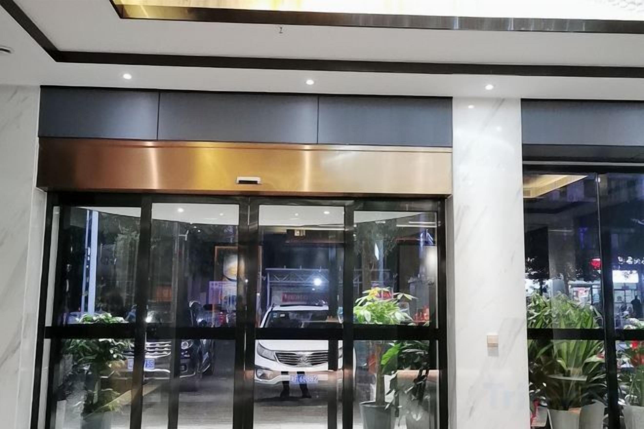 A hotel entrance with a glass door, a metal frame, and a ceiling with recessed lighting.
