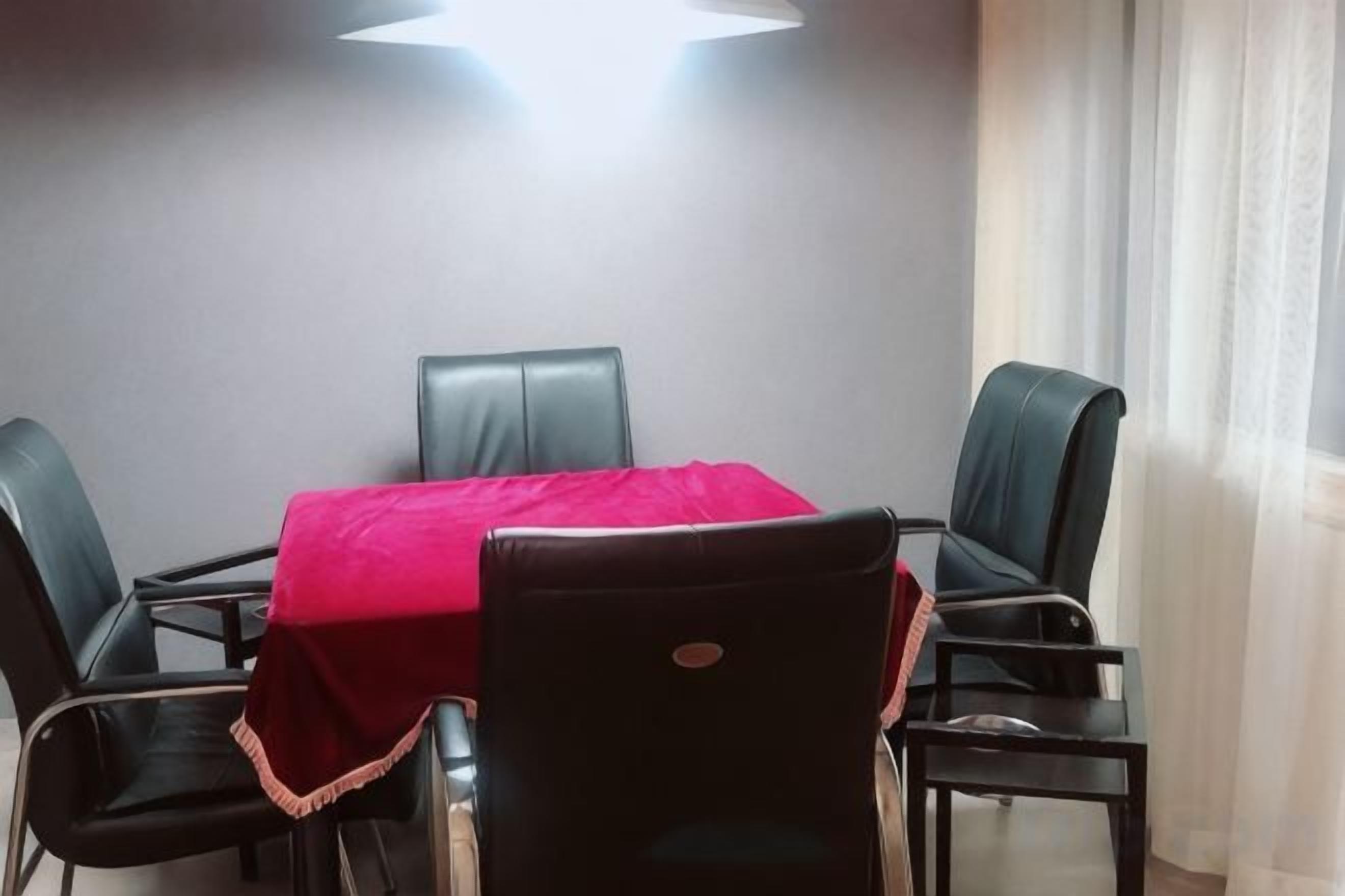 A conference room with a table, four chairs, and a red tablecloth.
